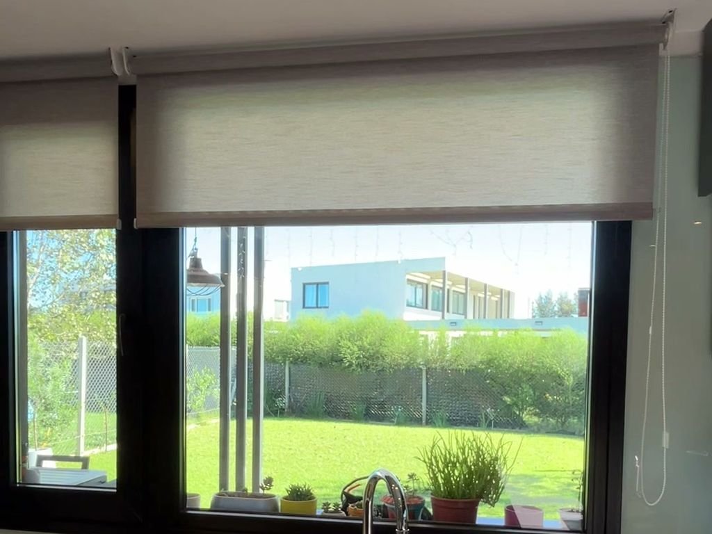 Cortina roller sunscreen sobre la mesada de una cocina con vista al jardín