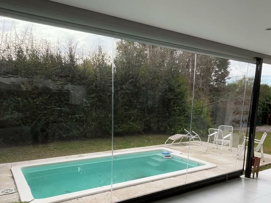 Toldo vertical de lona cristal cerrando una galería con vista a la pileta