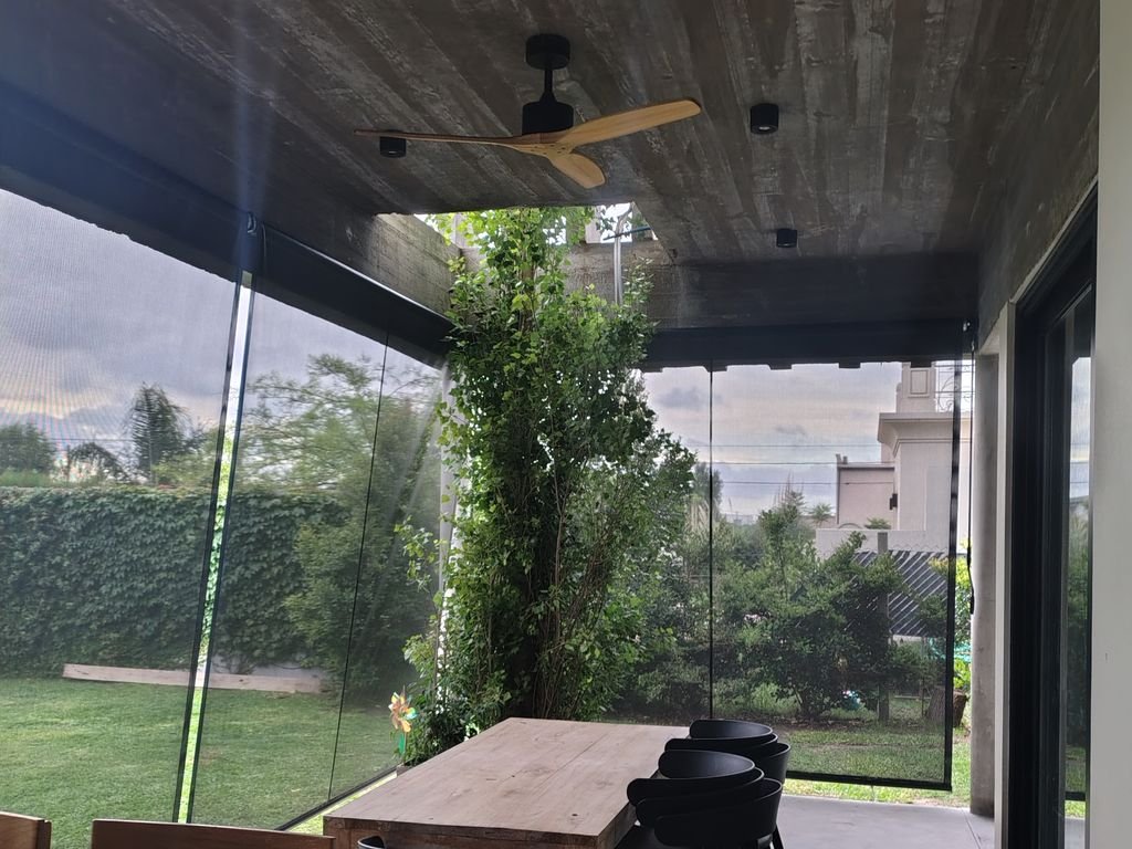 Toldo vertical de tela microperforada en la galería de una casa moderna
