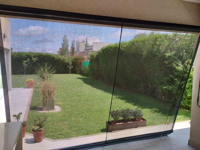Galería cerrada con toldos verticales de lona cristal y vista al jardín