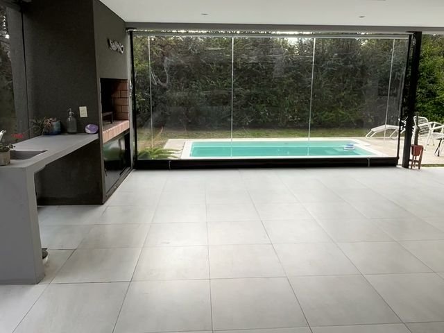 Galería cerrada con toldos de lona cristal y vista a la pileta