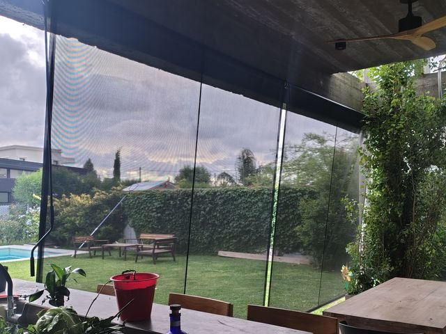 Toldo vertical microperforado en la galería de hormigón de una casa moderna