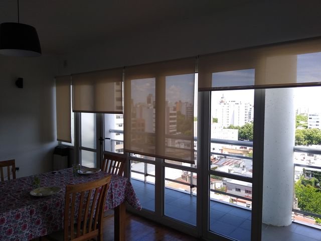 Cortinas roller sunscreen en el ventanal de un departamento con vista a la ciudad