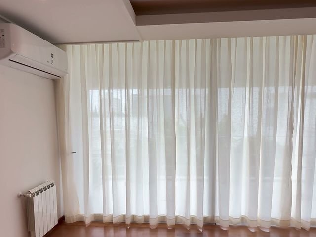 Cortinado de voile blanco de piso a techo en un living